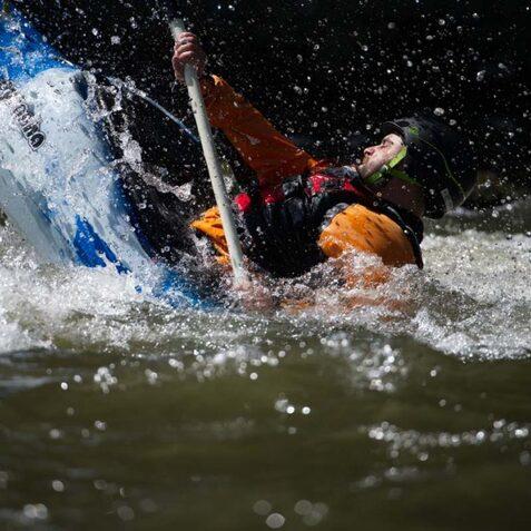 Kanufahrer kippt im Wasser, spritzt Wasser auf, w&auml;hrend er mit einem Paddel den Balanceakt versucht.
