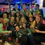 Gruppe von fr&ouml;hlichen Menschen in bunten Kost&uuml;men posiert gemeinsam in einer festlich dekorierten Umgebung.