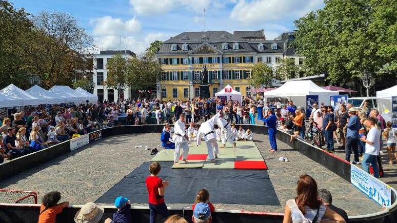 Judo-Demonstration auf einem sportlichen Event mit Zuschauer-Ensemble auf einem Platz. Zelt-St&auml;nde im Hintergrund.