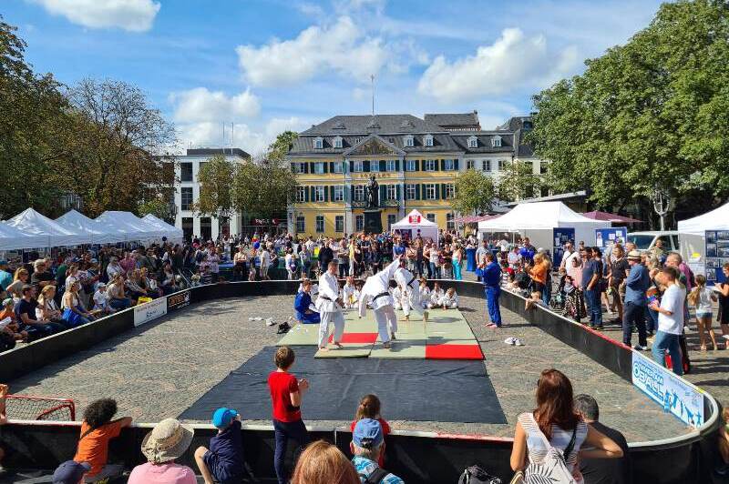 Judo-Demonstration auf einem sportlichen Event mit Zuschauer-Ensemble auf einem Platz. Zelt-St&auml;nde im Hintergrund.