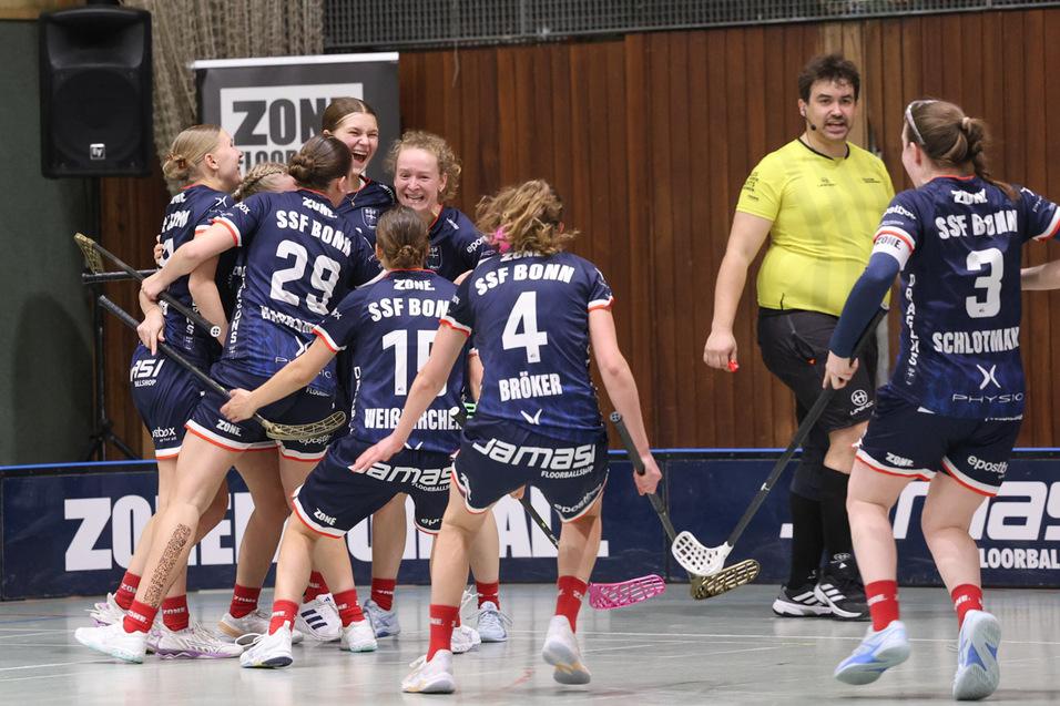 Acht Frauenfeiern im Teamtrikot von SSF Bonn, w&auml;hrend ein Schiedsrichter neben ihnen steht.