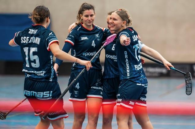 Vier Basketballspielerinnen umarmen sich freudig auf dem Spielfeld, mit Schl&auml;gern in der Hand und Teamdress.