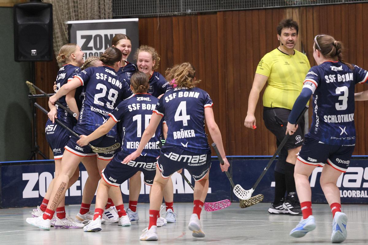 Acht Frauenfeiern im Teamtrikot von SSF Bonn, w&auml;hrend ein Schiedsrichter neben ihnen steht.