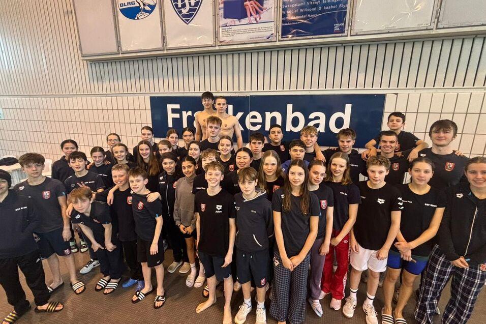 Gruppenfoto von 44 Jugendlichen in Schwimmbekleidung vor einem Schild mit der Aufschrift &bdquo;Freibad&ldquo;.
