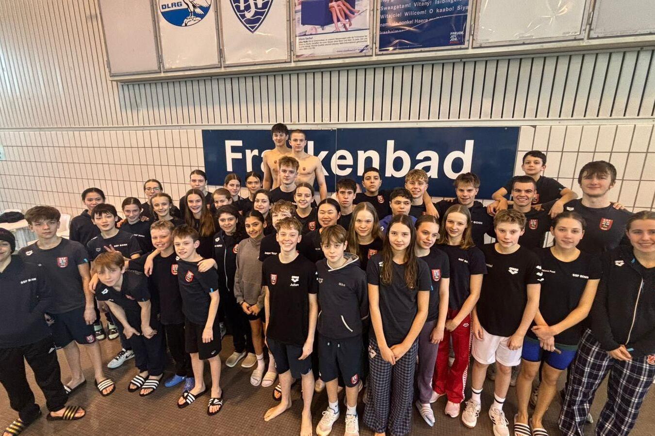 Gruppenfoto von 44 Jugendlichen in Schwimmbekleidung vor einem Schild mit der Aufschrift &bdquo;Freibad&ldquo;.