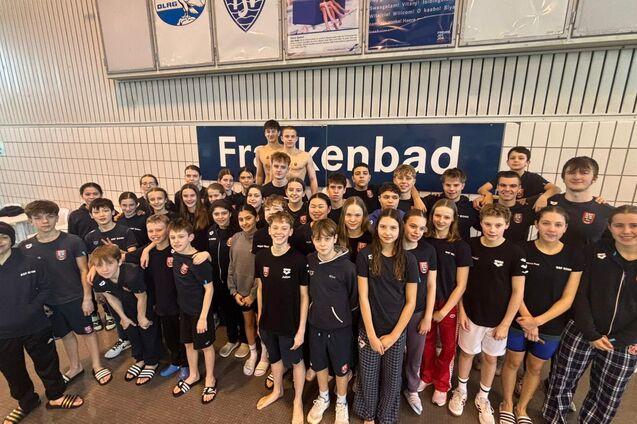 Gruppenfoto von 44 Jugendlichen in Schwimmbekleidung vor einem Schild mit der Aufschrift &bdquo;Freibad&ldquo;.