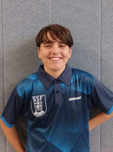 Junger Sportler mit lächelndem Gesicht, in einem blauen Tischtennisshirt mit Logo des SSF Bonn.