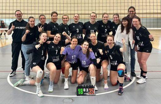 Mannschaftsfoto einer weiblichen Volleyballmannschaft mit Trainer, l&auml;chelnd und jubelnd nach einem Spiel.
