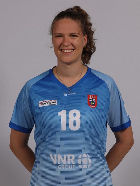 L&auml;chelnde junge Frau tr&auml;gt ein himmelblaues Trikot mit der Nummer 18 und Logos auf einem neutralen Hintergrund.