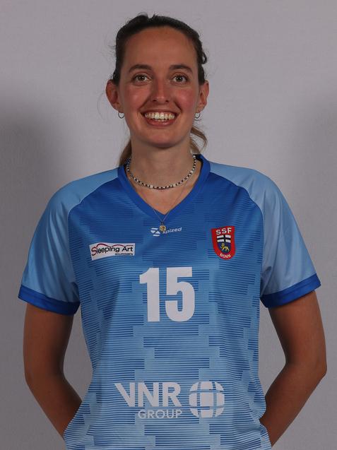 L&auml;chelnde Frau tr&auml;gt ein hellblaues Trikot mit der Nummer 15 und Logos, vor einem neutralen Hintergrund.