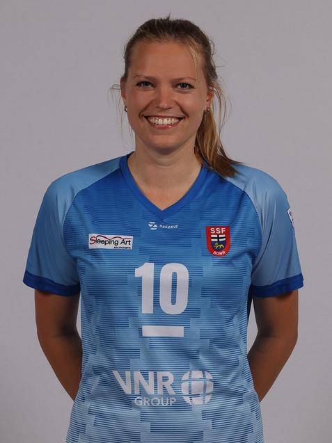 L&auml;chelnde Frau in blauer Sporttrikot mit der Nummer 10, steht vor einem neutralen Hintergrund.