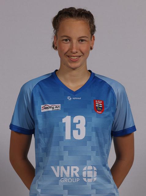 Portrait einer Sportlerin in einem blauen Trikot mit der Nummer 13 und Logos von Sponsoren. Sie l&auml;chelt in die Kamera.