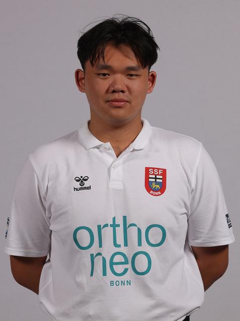 Portrait eines jungen Mannes in wei&szlig;em Trikot mit dem Logo &bdquo;SSB Bonn&ldquo; und &bdquo;orthoneo&ldquo;, dunkelgraze Shorts.