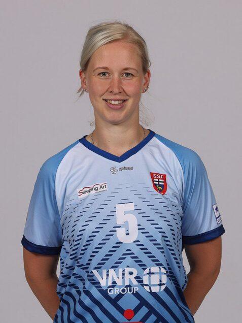 Portrait einer sportlichen Frau in einem blauen Trikot mit der Nummer 5 und Logos auf der Vorderseite.