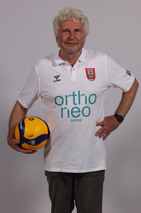&Auml;lterer Mann h&auml;lt einen Volleyball in der Hand, tr&auml;gt ein wei&szlig;es Polo-Shirt mit dem Logo "SSF Bonn".