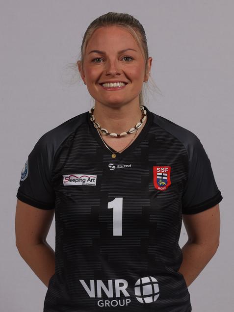 Portr&auml;t einer l&auml;chelnden Frau in schwarzem Trikot mit der Nummer 1 und Markenlogos, vor neutralem Hintergrund.