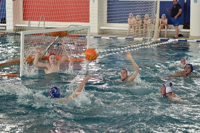 Wasserballspiel: Spieler werfen einen Ball auf das Tor, w&auml;hrend der Torwart zum Abwehren bereit ist.