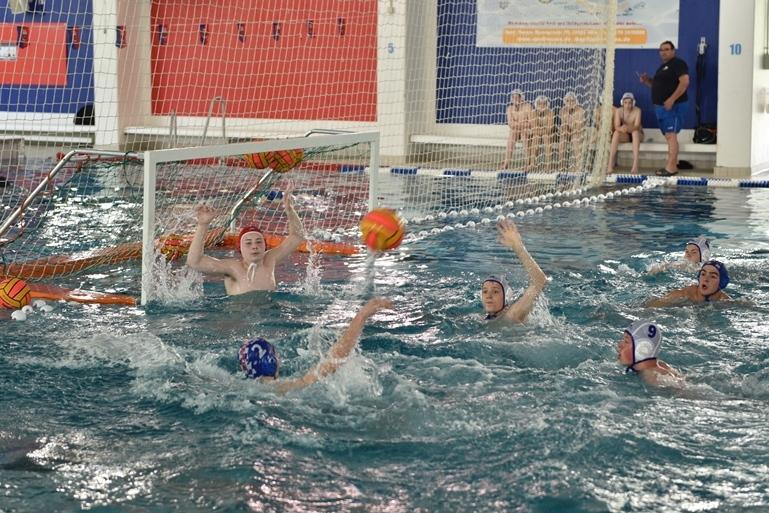 Wasserballspiel: Spieler werfen einen Ball auf das Tor, w&auml;hrend der Torwart zum Abwehren bereit ist.