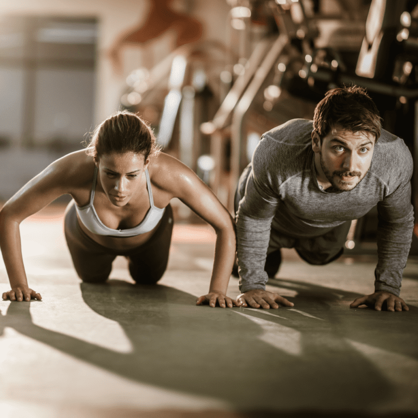 Zwei Personen machen im Fitnessstudio Liegest&uuml;tze auf einer gr&uuml;nen Trainingsmatte.