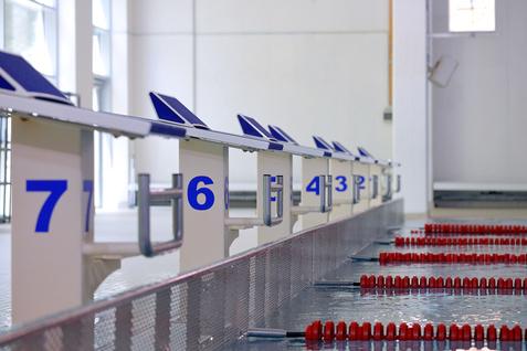 Startbl&ouml;cke mit Nummern f&uuml;r Wettk&auml;mpfe entlang einer Schwimmstrecke in einer Wettkampfbadumgebung.