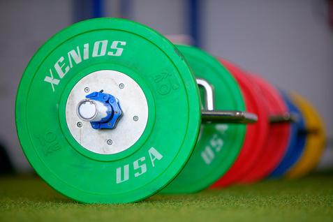 Nahaufnahme von Gewichtsscheiben in verschiedenen Farben auf einer Langhantel im Trainingsraum.