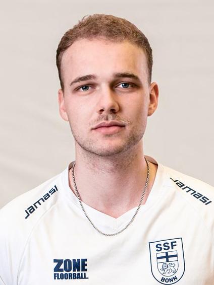 Portrait eines jungen Mannes in wei&szlig;em Sporttrikot mit der Nummer 7, l&auml;chelt vor neutralem Hintergrund.