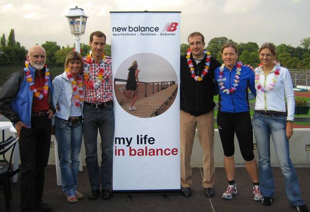 Gruppenshooting von sechs Personen mit Blumenkr&auml;nzen, Stehtafel von New Balance im Hintergrund.