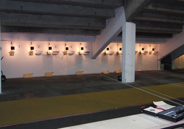 Schie&szlig;stand mit zehn Zielanlagen, beleuchtet, und einem Teppichboden im Vordergrund.