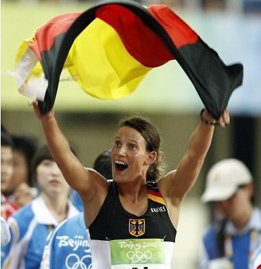 Athletin in Sportkleidung jubelt mit einer Deutschlandflagge w&auml;hrend der Olympischen Spiele 2008 in Peking.