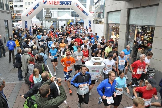 Eine Menschenmenge l&auml;uft unter einem INTERSPORT-Bogen, Zuschauer beobachten das Event aus der N&auml;he.