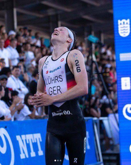 Athlet in Wettkampfdress mit der Nummer 26 jubelt im Ziel, umgeben von jubelnden Zuschauern.