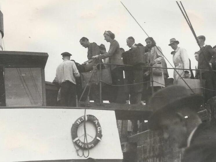 Menschen laden Gep&auml;ck auf ein Schiff, w&auml;hrend andere auf dem Anleger warten; historische Schwarz-Wei&szlig;-Fotografie.