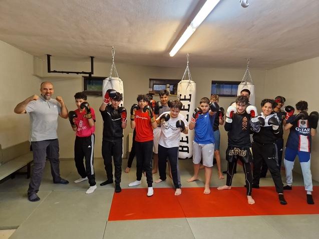 Gruppentraining im Boxen mit Jugendlichen, die Boxhandschuhe tragen, in einem Trainingsraum mit Boxs&auml;cken.